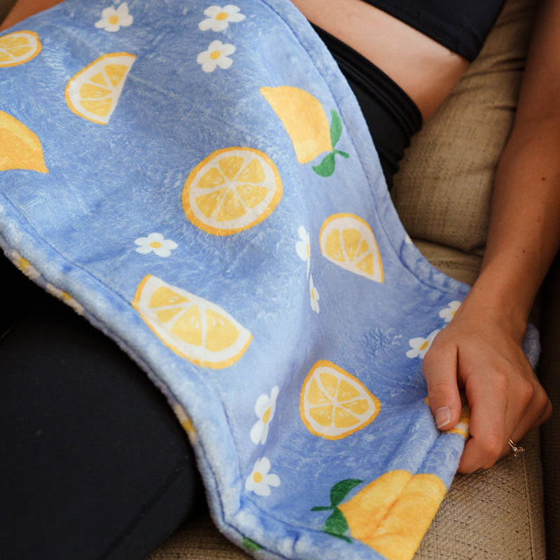 Person holding a blue cute Rosie heating pad with lemon pattern